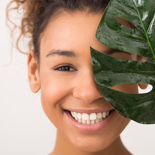 Image of a young woman smiling behind a leaf