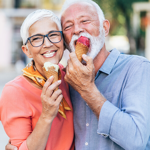 An older couple eating ice cream cones while hugging