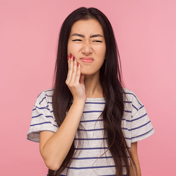 Close up of a woman holding her jaw in pain