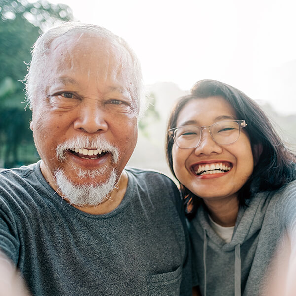 An older man smiling with bright teeth next to a young woman